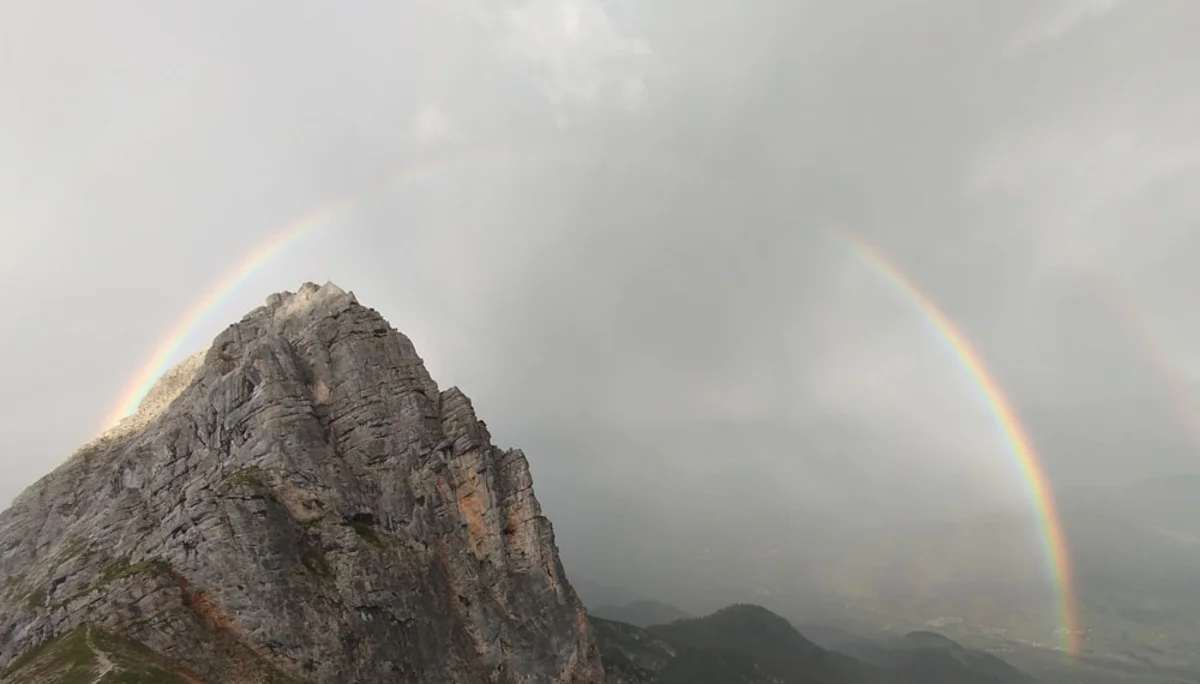 Regenbogen über einem felsigen Berggipfel mit bewölktem Himmel | © Florian Ludwig