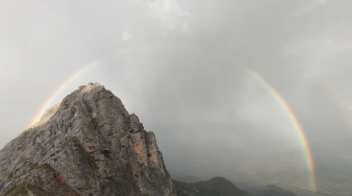 Regenbogen über einem felsigen Berggipfel mit bewölktem Himmel | © Florian Ludwig
