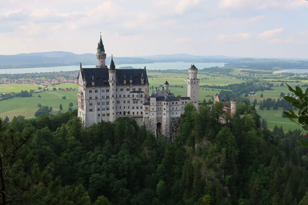 Schloss Neuschwanstein auf bewaldetem Hügel mit Blick auf Seen und grüne Landschaft im Hintergrund | © Christian Stadtmüller