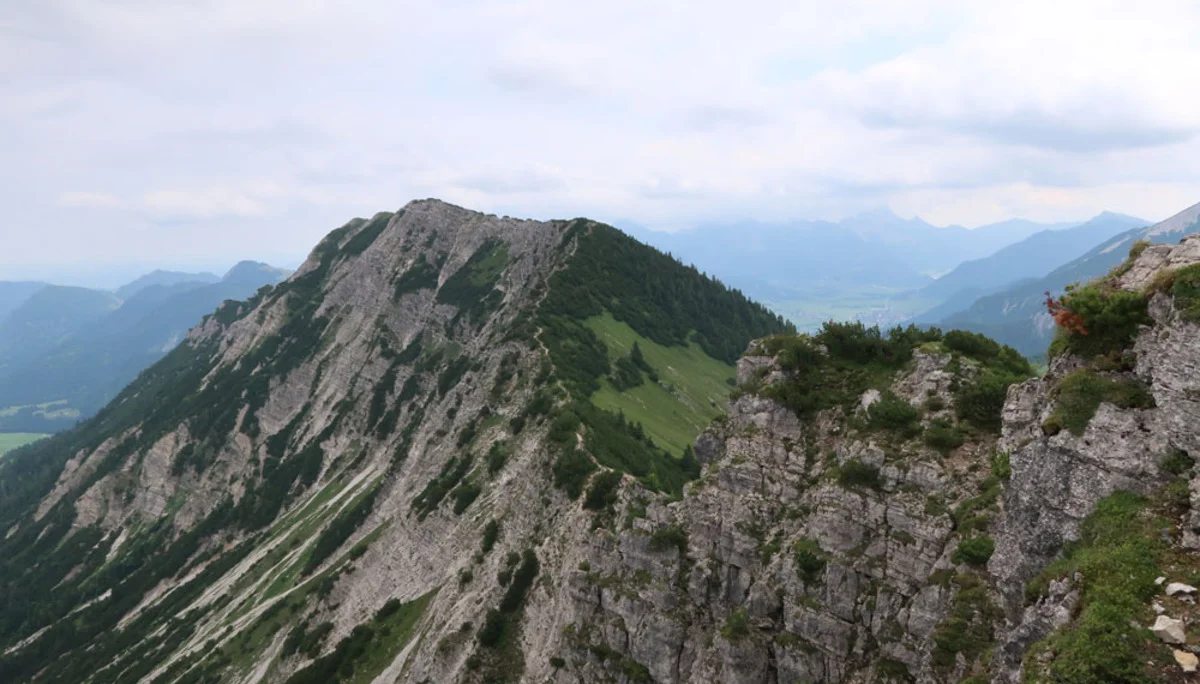 Bergkamm mit steilen Felswänden und bewachsenen Hängen unter bewölktem Himmel | © Christian Stadtmüller