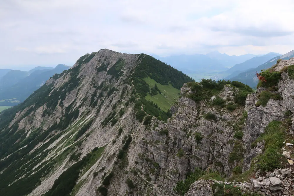 Bergkamm mit steilen Felswänden und bewachsenen Hängen unter bewölktem Himmel | © Christian Stadtmüller